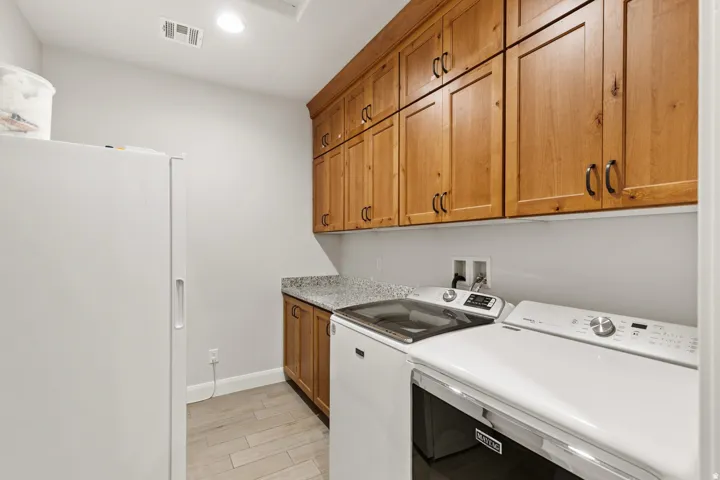 Laundry room featuring light wood finished floors, separate washer and dryer, cabinet space, and recessed lighting