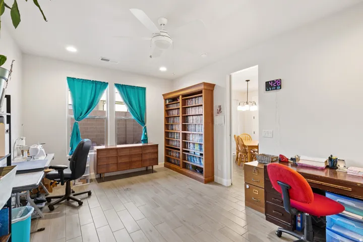 Home office with wood finish floors, a ceiling fan, and suspended lighting