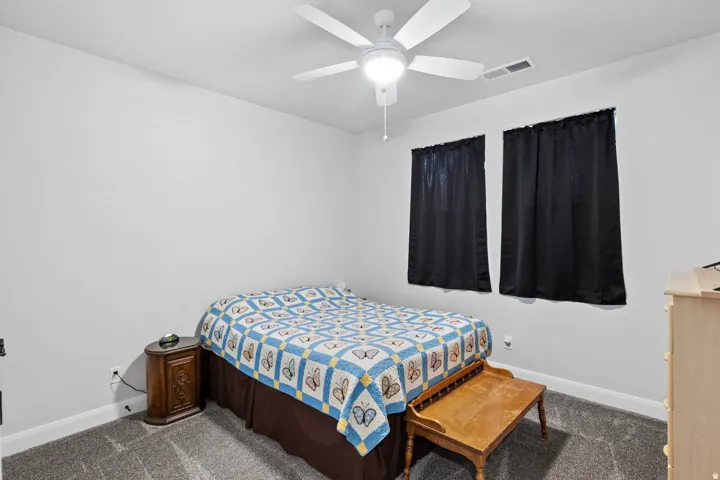 Bedroom with dark colored carpet and ceiling fan