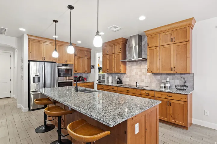 Kitchen featuring light stone countertops, a breakfast bar, stainless steel appliances, and wood tiled floors