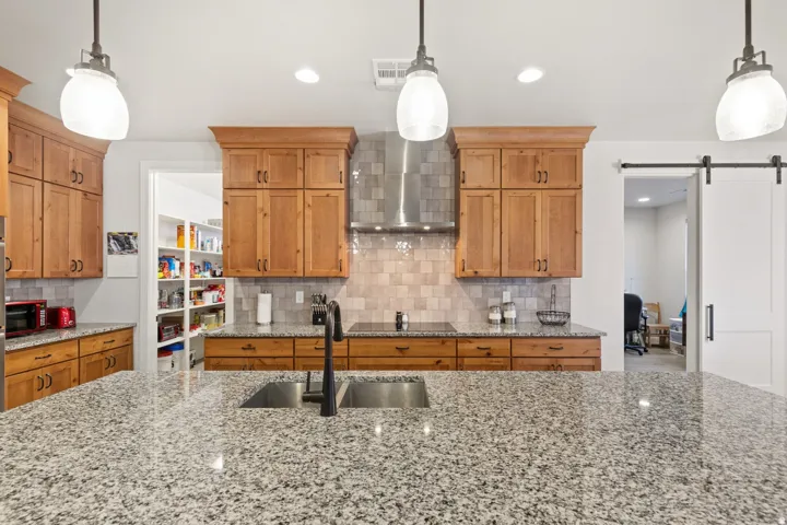 Kitchen with wood finish cabinets, decorative light fixtures, and a barn door
