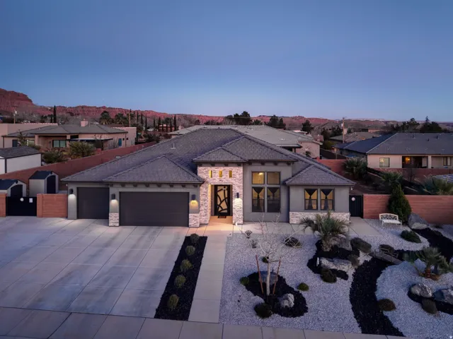 View of front facade with a garage, driveway, a residential view, stone siding, and stucco siding