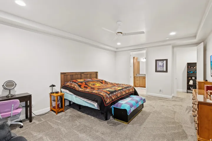 Bedroom featuring recessed lighting, light carpet, ceiling fan, connected bathroom, and a raised ceiling