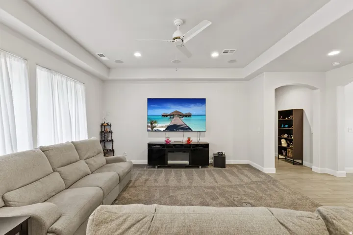 Living room featuring a ceiling fan, light wood-type flooring, arched walkways, and recessed lighting