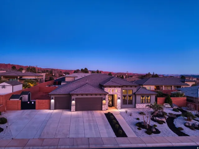 View of front of property featuring an attached garage, stone siding, a residential view, driveway, and stucco siding