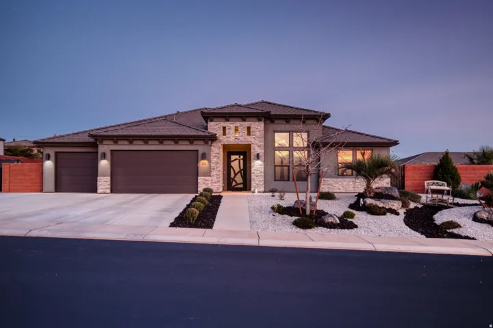 Prairie-style house featuring stone siding, an attached garage, driveway, stucco siding, and a tile roof