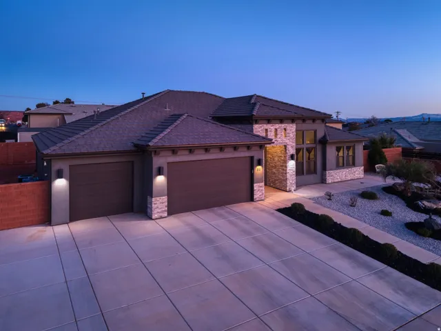 View of front of home featuring an attached garage, stone siding, concrete driveway, and stucco siding