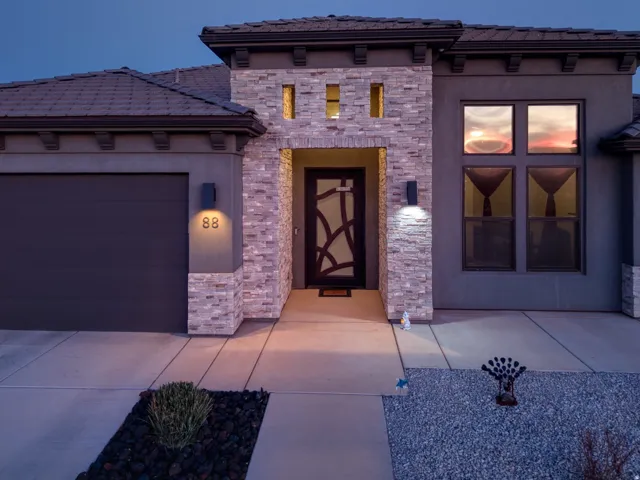 View of front of house featuring a tile roof, stucco siding, a garage, and stone siding