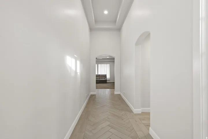 Corridor featuring arched walkways, a high ceiling, parquet floors, and recessed lighting