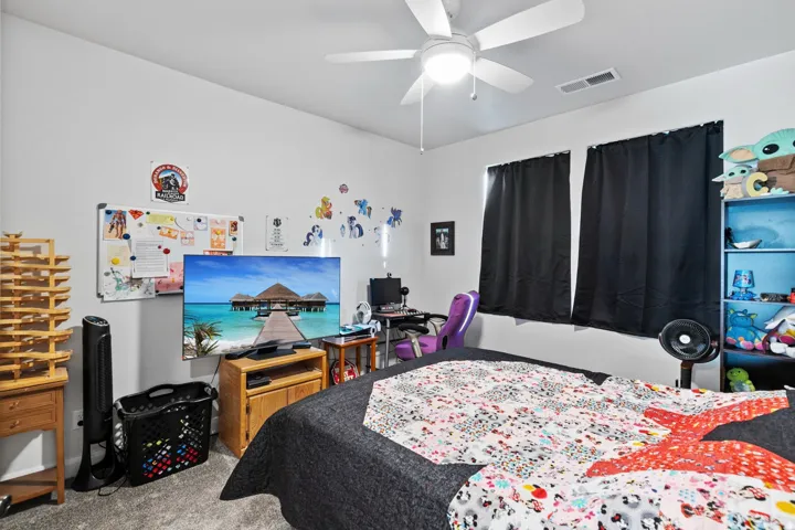 Carpeted bedroom featuring ceiling fan