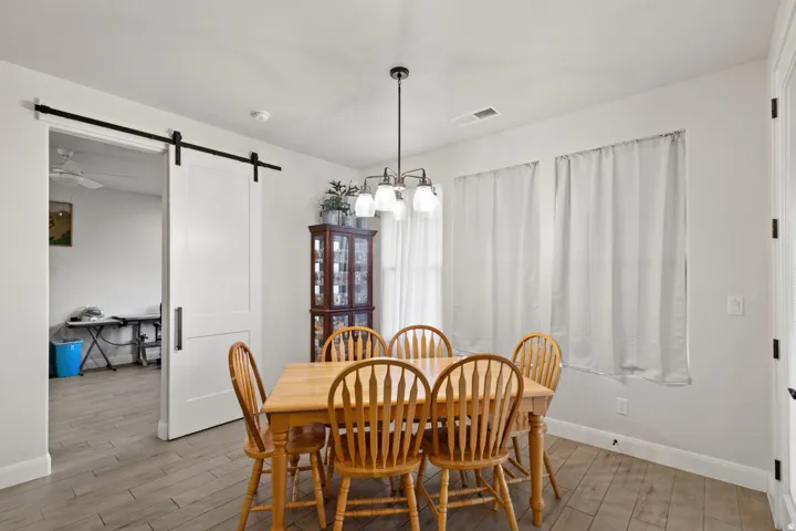 Dining area featuring a barn door, light wood-style flooring, and suspended lighting