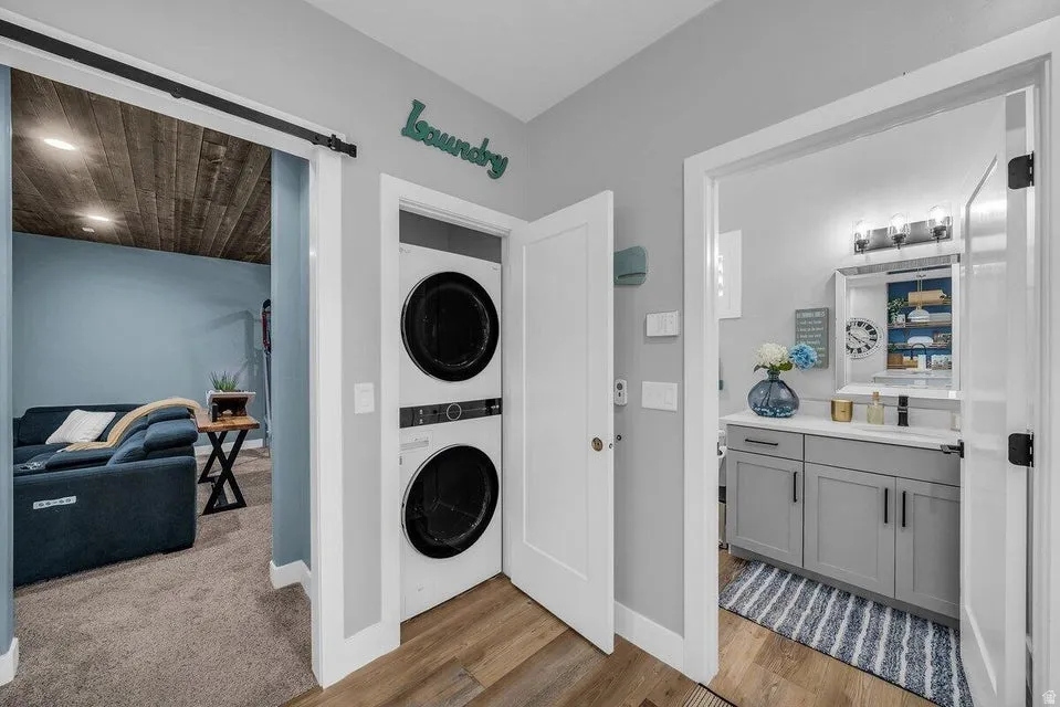 Laundry room with stacked washer / dryer and light wood-type flooring