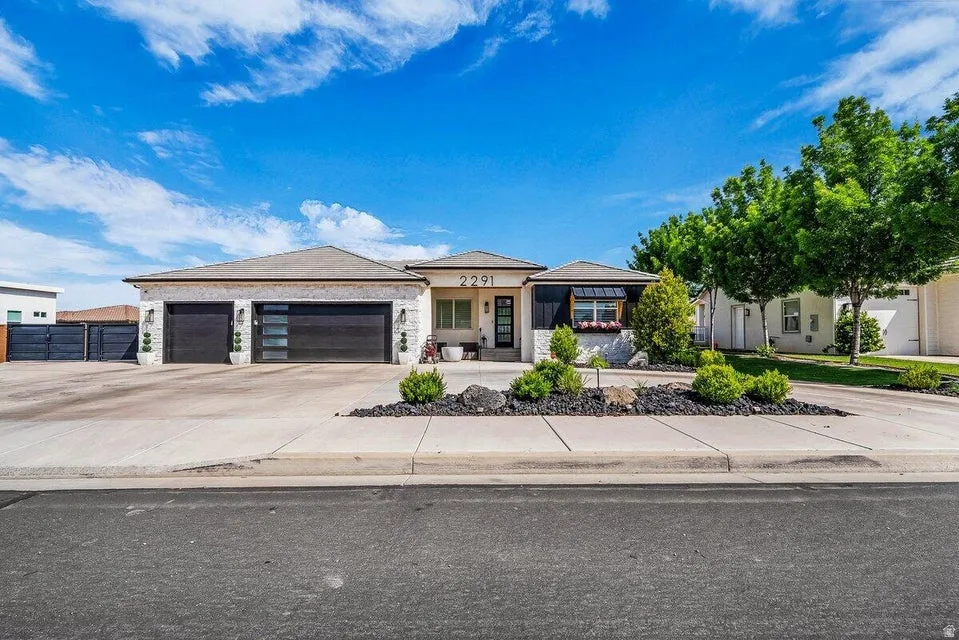 Prairie-style home featuring an attached garage, concrete driveway, a porch, and stone siding