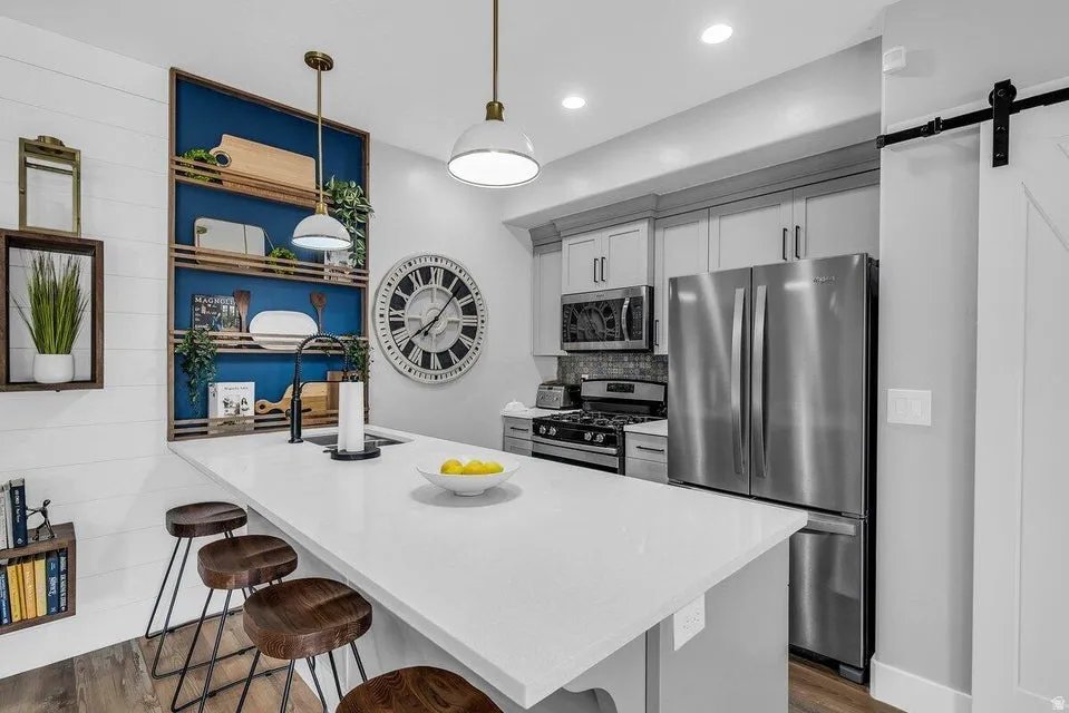 Kitchen with a kitchen bar, a peninsula, stainless steel appliances, a barn door, and open shelves