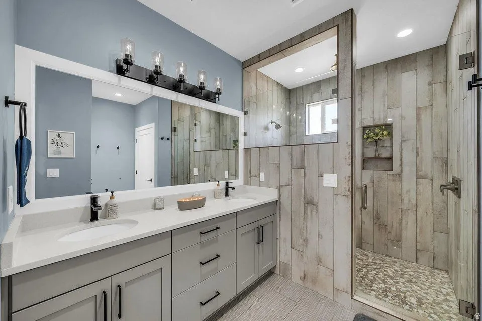 Full bath featuring double vanity and a stall shower