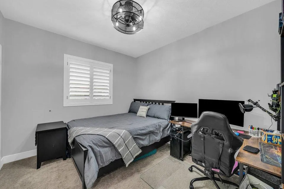 Carpeted bedroom featuring a desk and baseboards