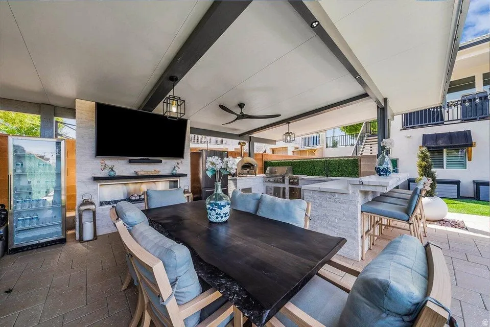 View of patio with exterior kitchen, a ceiling fan, and an outdoor bar and dining area