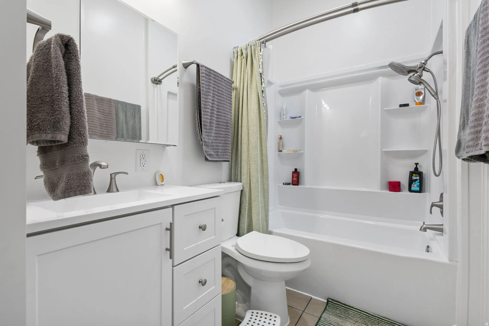 Bathroom featuring vanity, shower / bath combination with curtain, and light tile patterned floors