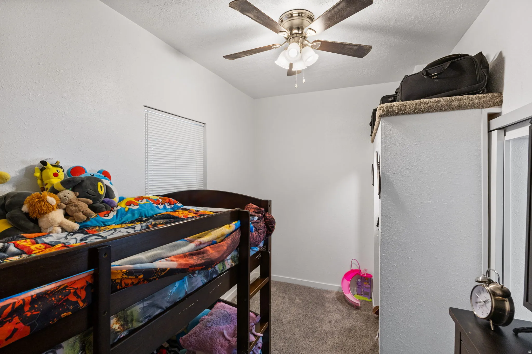 Bedroom featuring dark carpet, a ceiling fan, and a textured wall