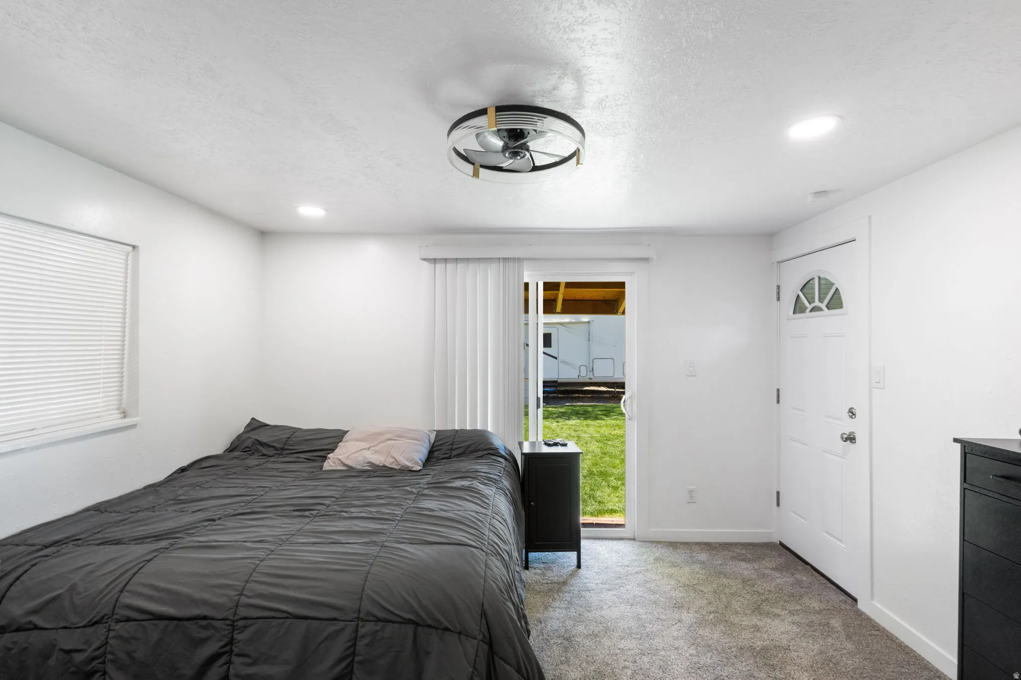 Carpeted bedroom with a textured ceiling, recessed lighting, and access to outside