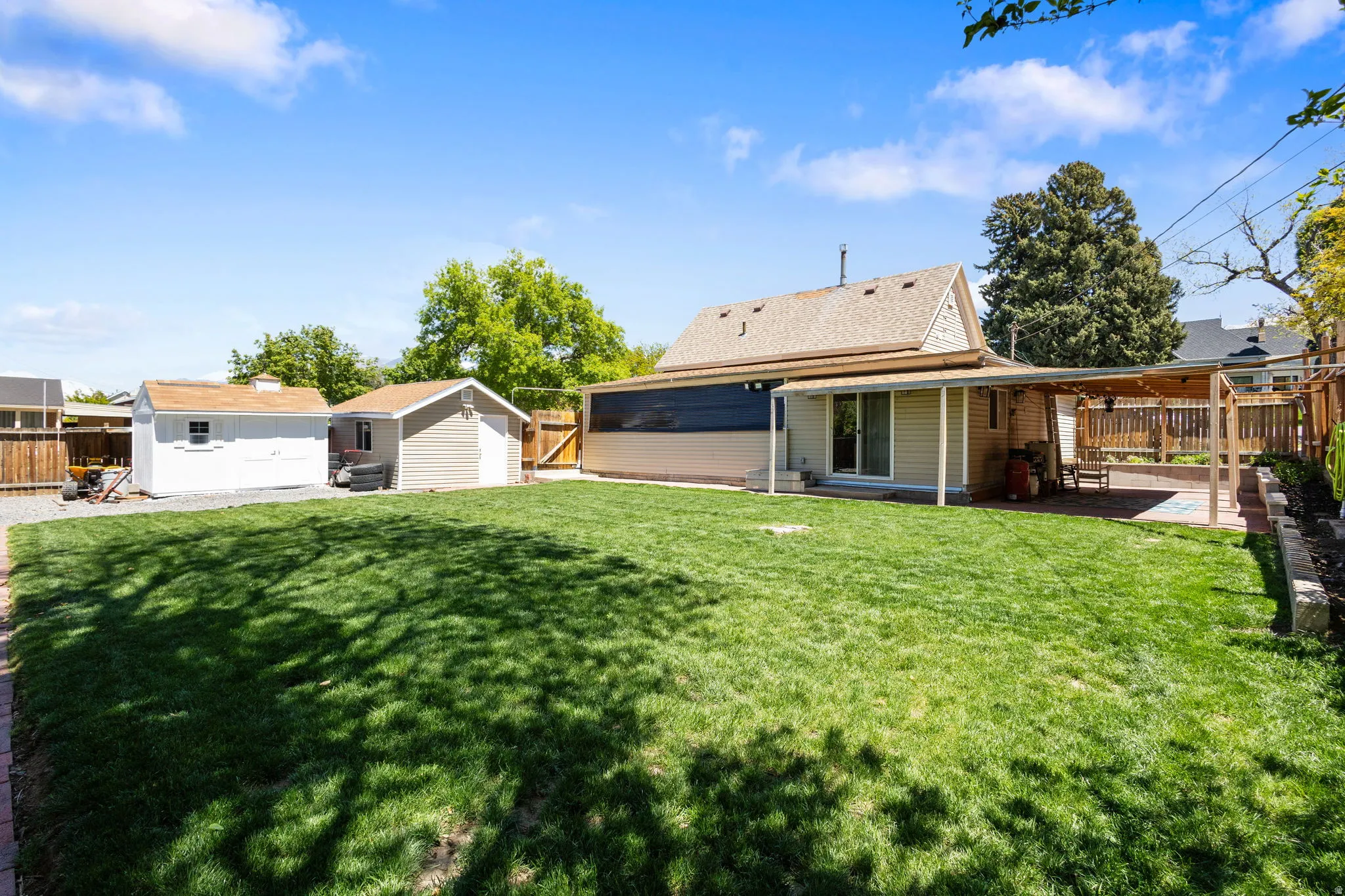 Rear view of property featuring a fenced backyard, a patio, and a storage unit