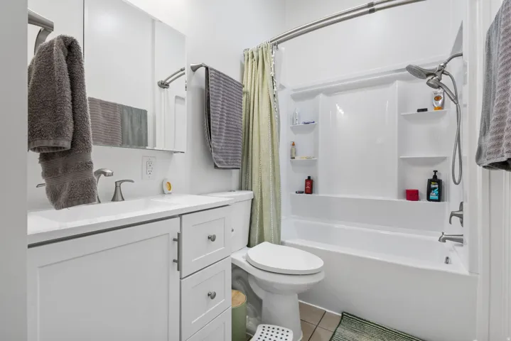 Bathroom featuring vanity, shower / bath combination with curtain, and light tile patterned floors