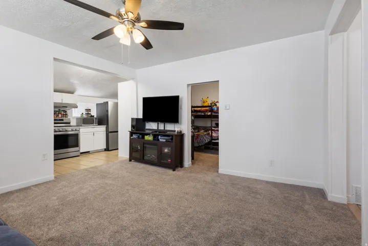 Living area with a textured ceiling, light carpet, and ceiling fan