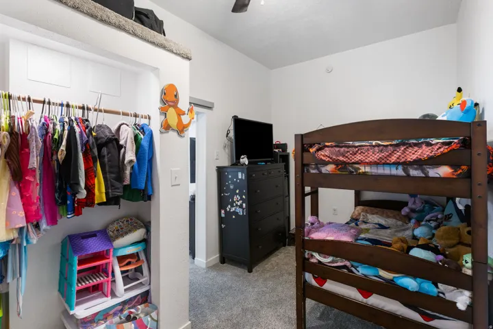 Bedroom with light colored carpet, a ceiling fan, and a closet