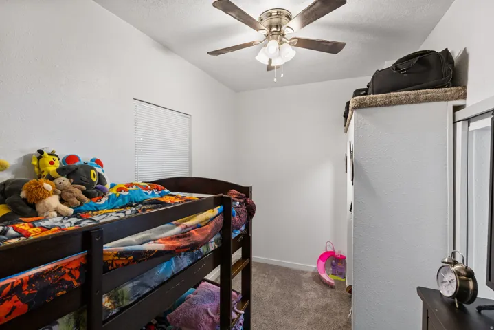 Bedroom featuring dark carpet, a ceiling fan, and a textured wall
