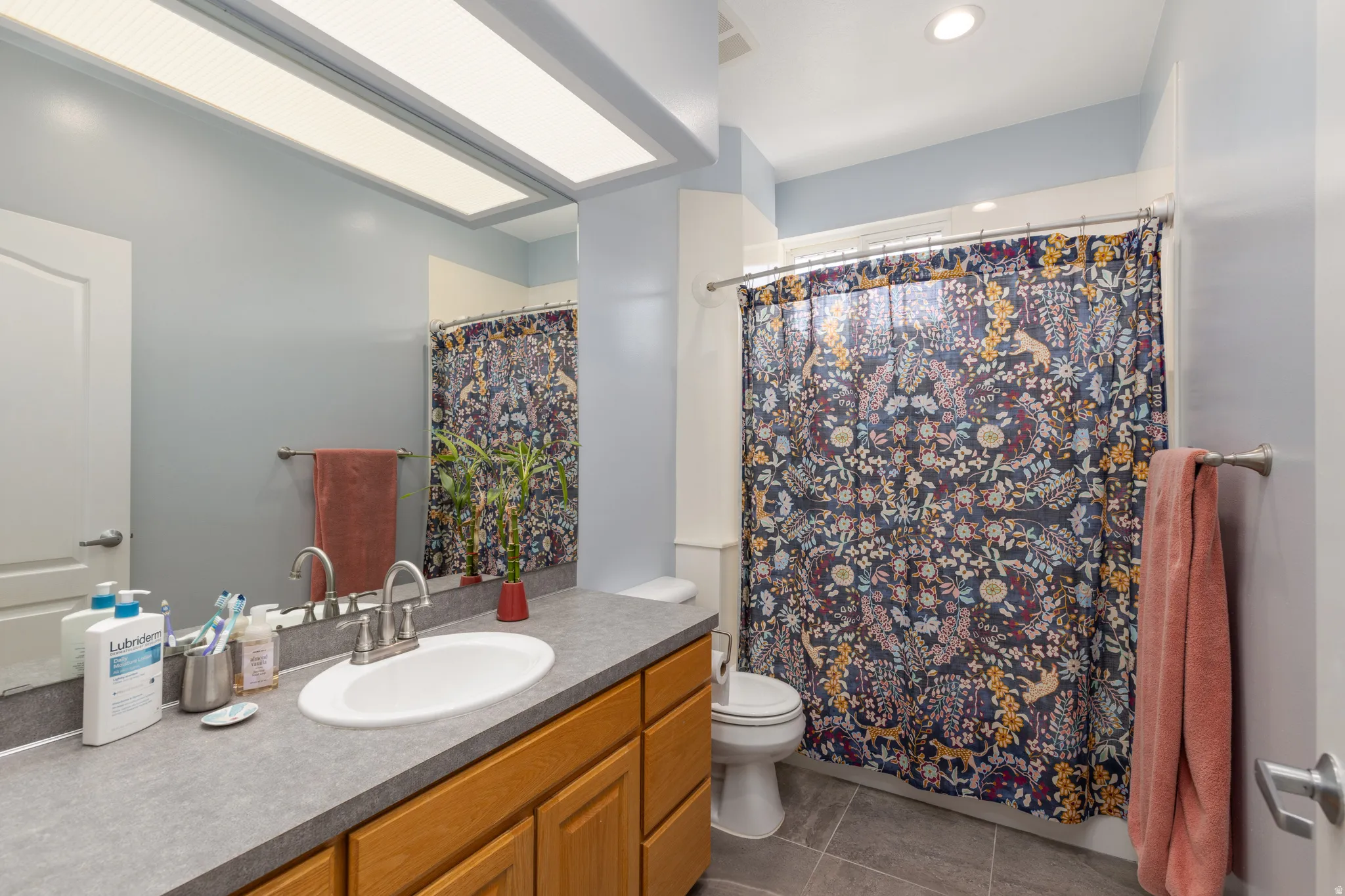 Bathroom with vanity, a shower with curtain, dark tile patterned flooring, and recessed lighting