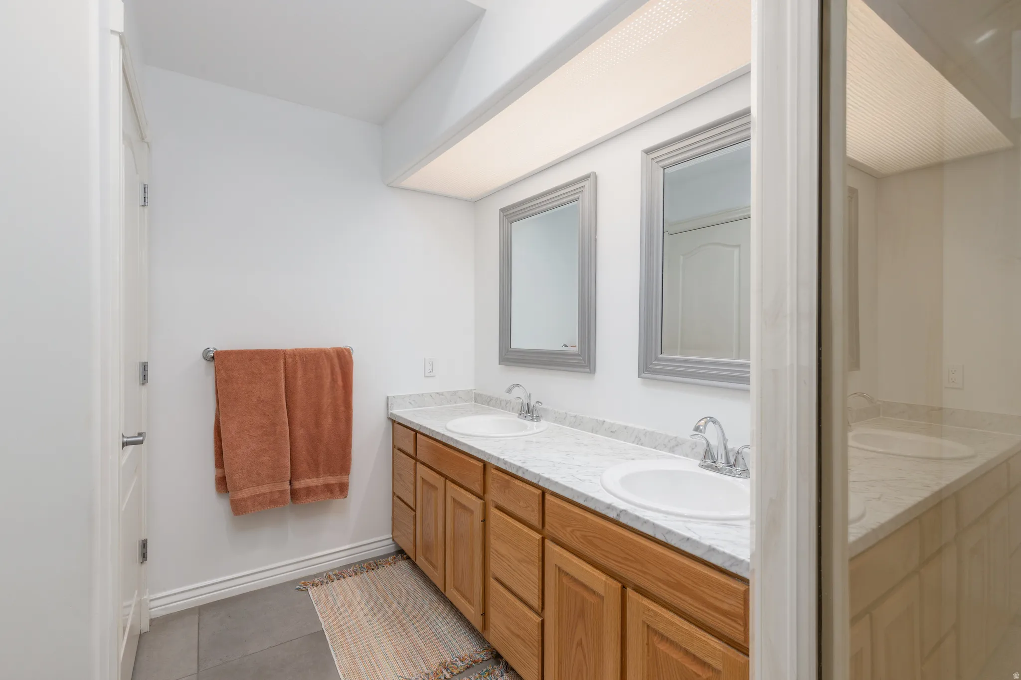 Bathroom with double vanity and light tile patterned floors