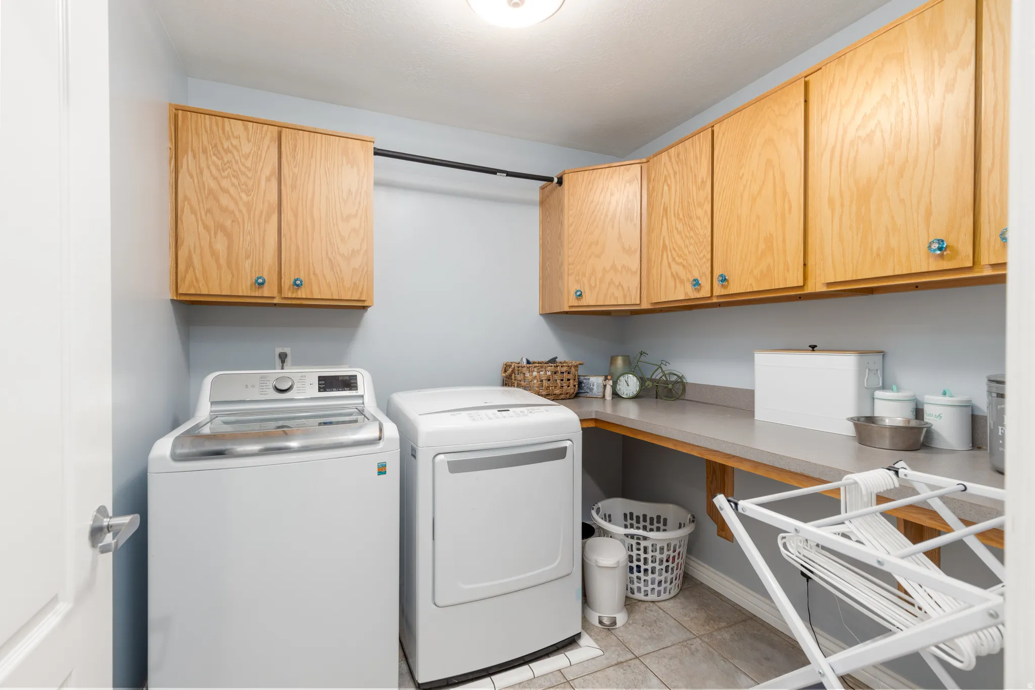Laundry area with washing machine and clothes dryer, cabinet space, and light tile patterned floors
