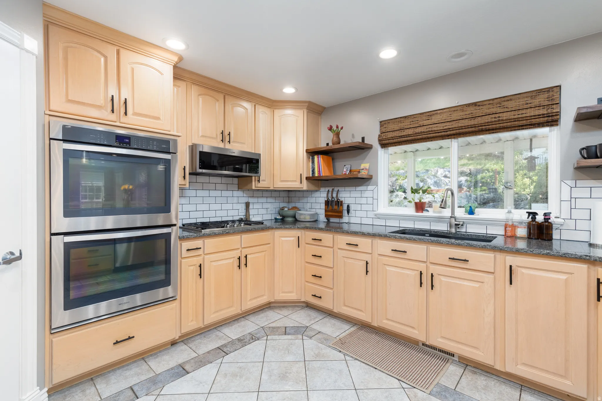 Kitchen featuring open shelves, light wood finish cabinetry, stainless steel appliances, dark stone countertops, and recessed lighting
