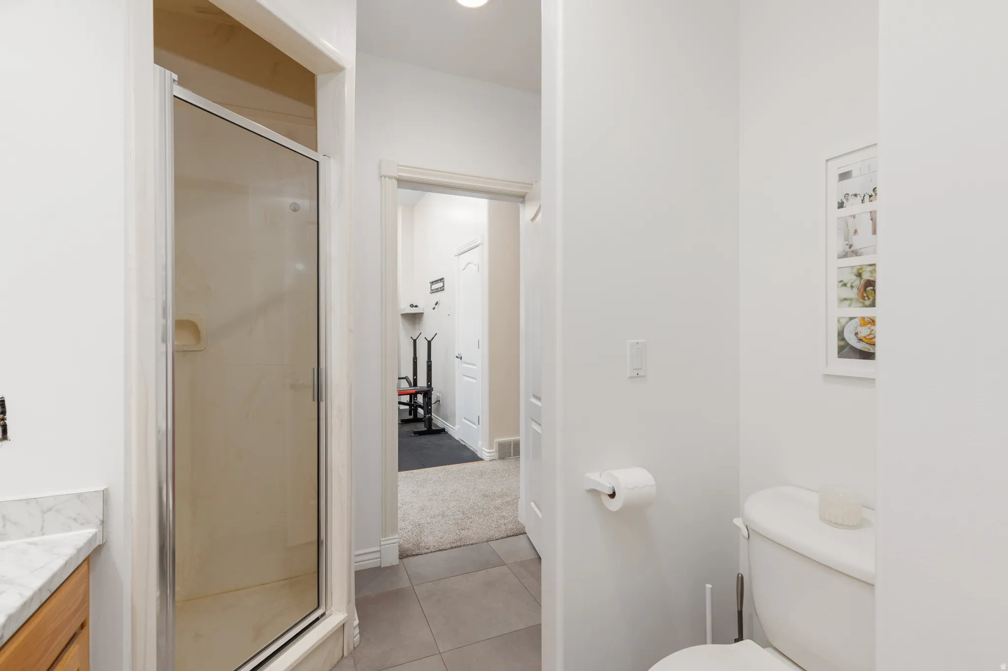 Bathroom with a stall shower, vanity, light tile patterned floors, and light carpet