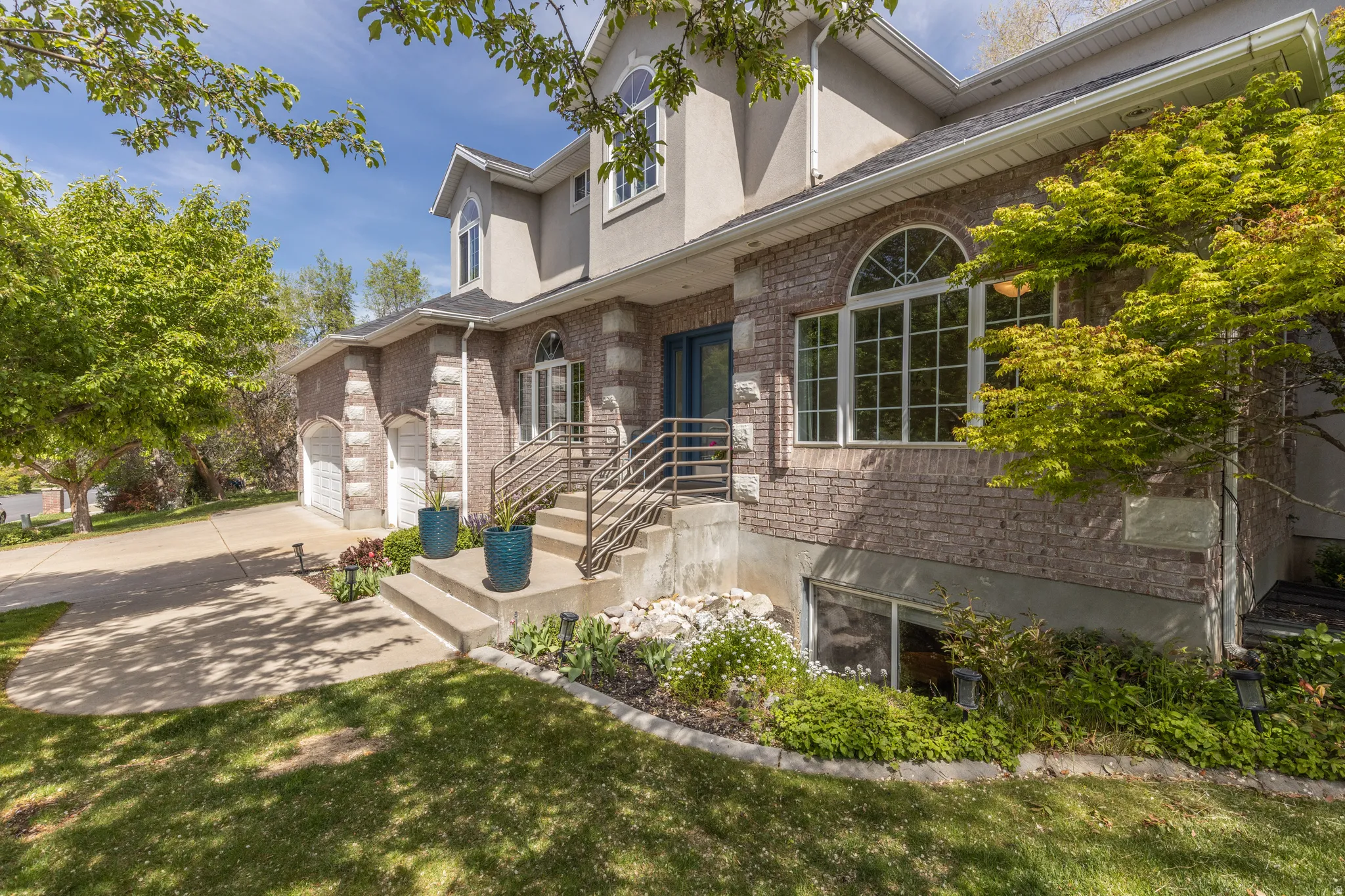 View of front facade with driveway, a garage, stucco siding, and brick siding