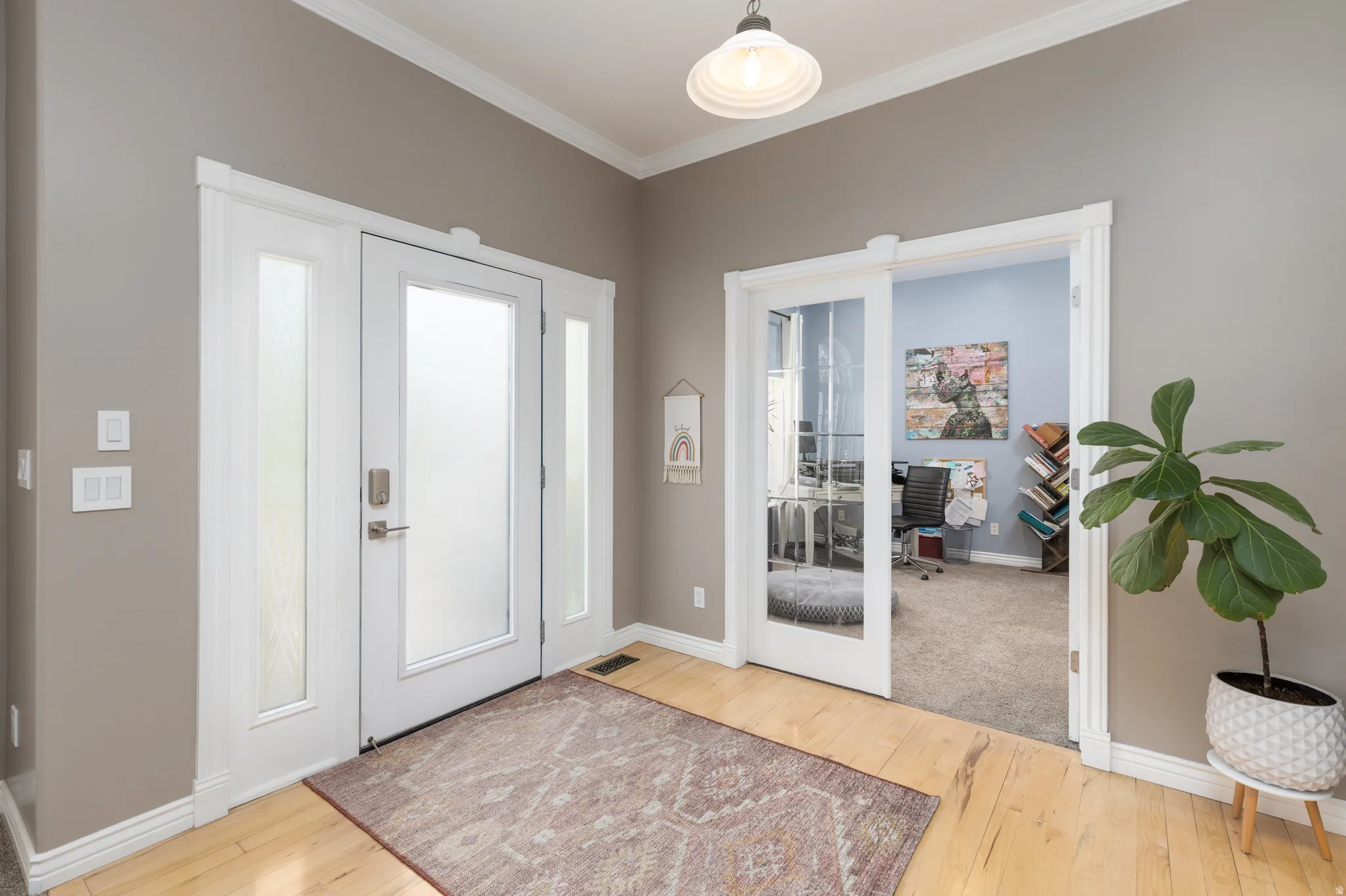 Entryway with light wood-style flooring and crown molding
