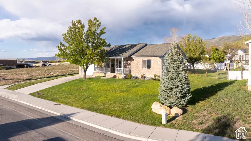 Ranch-style home with brick siding, a mountain view, a porch, and roof with shingles