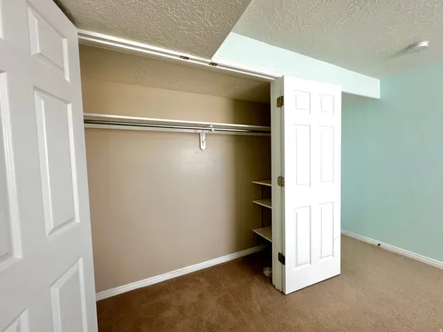 Bi-fold closet doors revealing a full-width hanging rod and integrated shelving