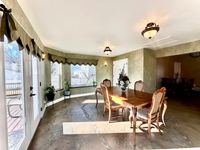 Dining area featuring a curved wall of windows, French doors to an outdoor deck, and tile flooring with decorative accents