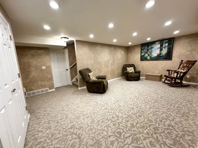 Spacious room featuring patterned carpet flooring, recessed ceiling lighting, and textured wall finishes