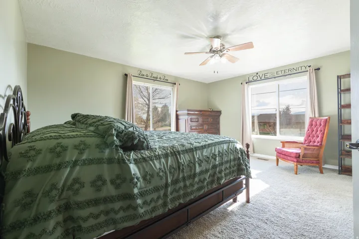Bedroom with light colored carpet, ceiling fan, and a textured ceiling