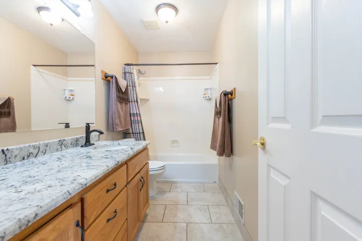 Full bath with vanity, light tile patterned floors, shower / bath combo, and a textured ceiling