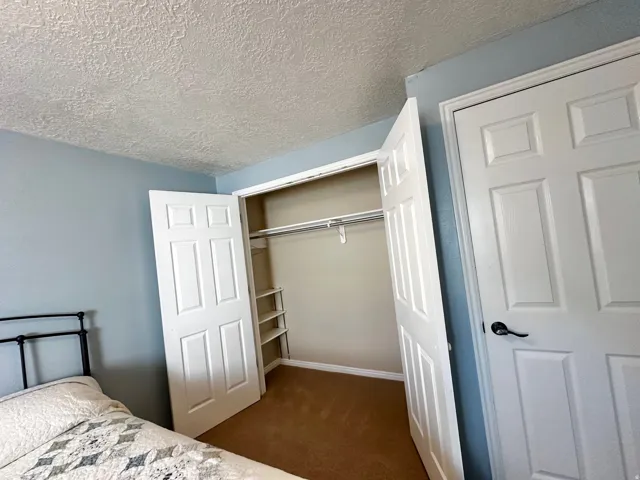 Built-in closet featuring bifold panel doors, hanging rod, and shelving