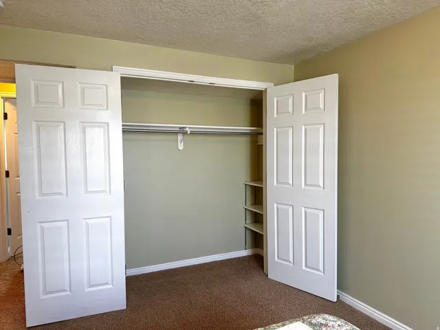 Recessed closet featuring bi-fold panel doors, upper shelving, hanging rod, and built-in side shelving