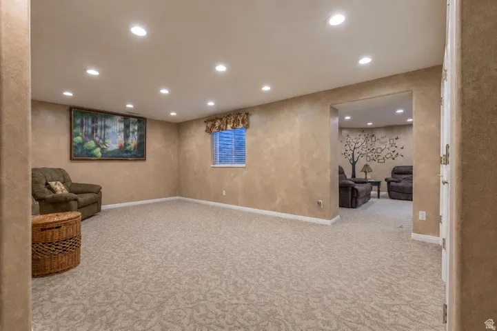 Carpeted recreation room with recessed lighting, textured walls, and a window with blinds