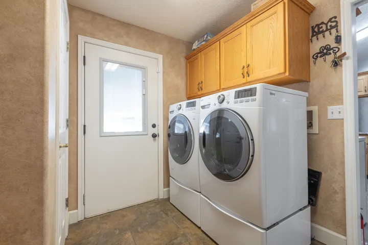 Laundry room with stone finish flooring, washer and clothes dryer, and cabinet space