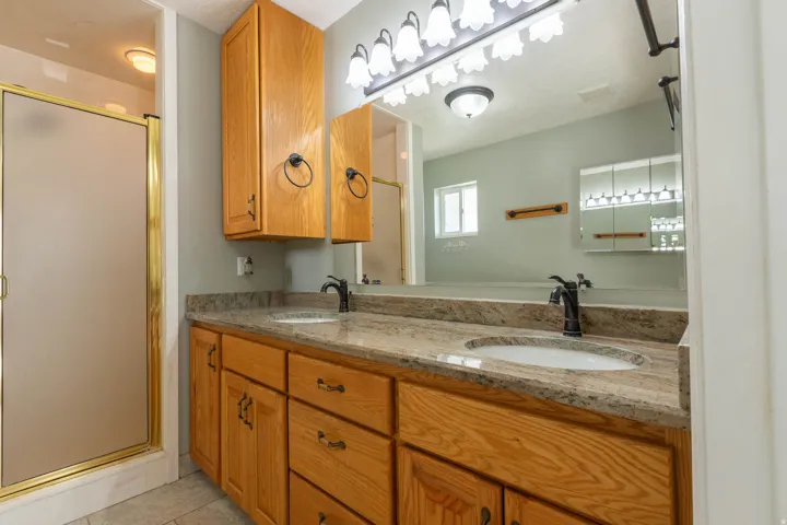 Full bathroom featuring double vanity, a shower stall, and light tile patterned flooring
