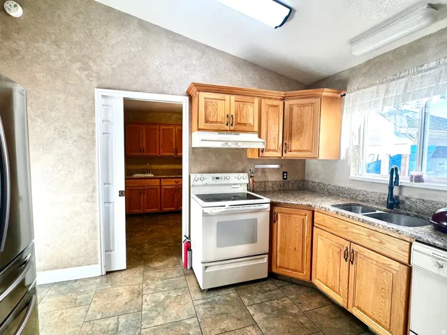Kitchen featuring wood cabinetry, granite-style countertops, and tile flooring