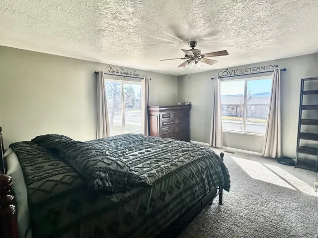 Spacious room featuring dual windows with ample natural light, a ceiling fan with light kit, and neutral wall tones