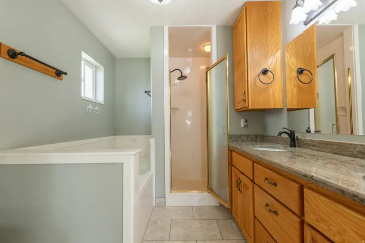 Bathroom with vanity, a bath, a textured ceiling, a shower stall, and light tile patterned floors